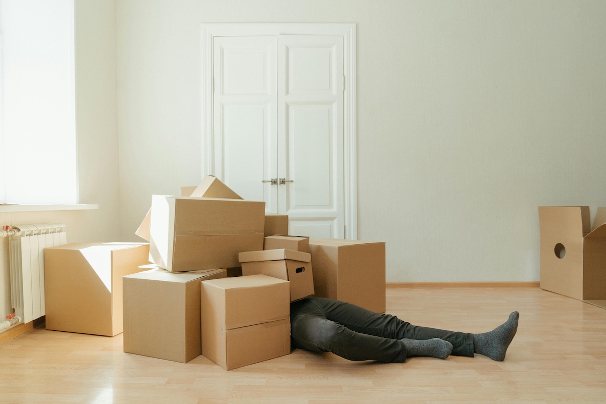 Person on floor under a pile of moving boxes.