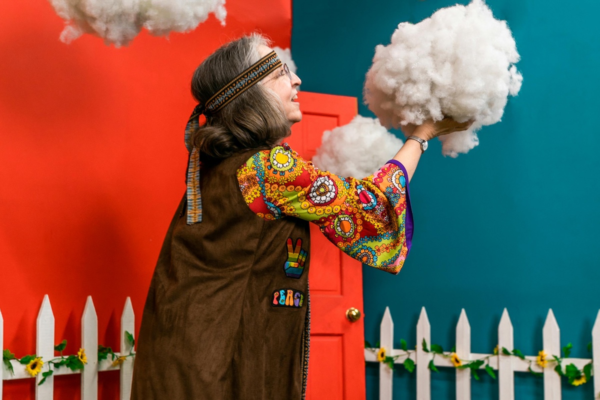 Elderly lady decorating a colorful room with cotton clouds.