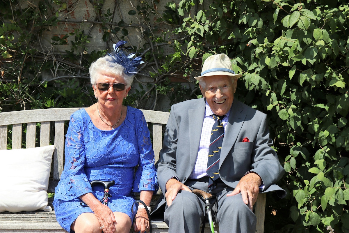 Happy older couple sitting on a park bench on a bright sunny day.
