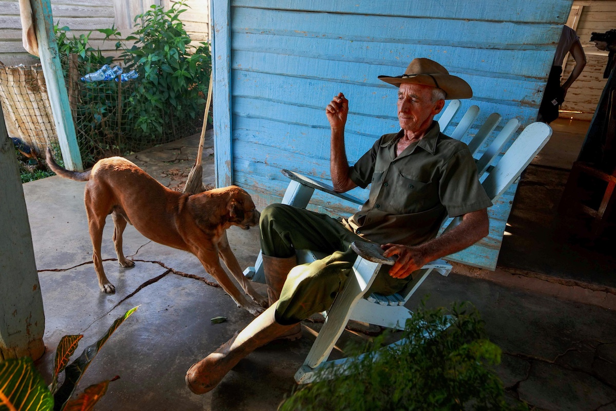 Old man sitting in a chair with his dog beside him.